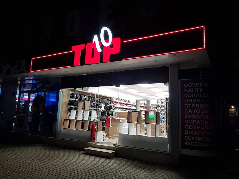 Светеща табела „TOP 10“ с червен LED контур над вход на магазин
